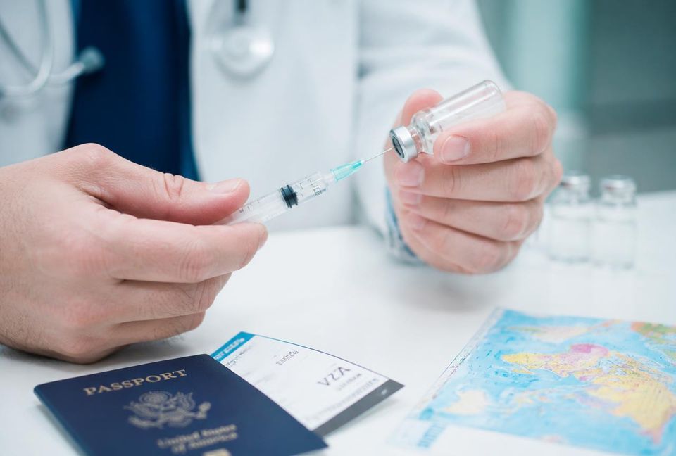 Doctor preparing a travel vaccine beside a passport and world map