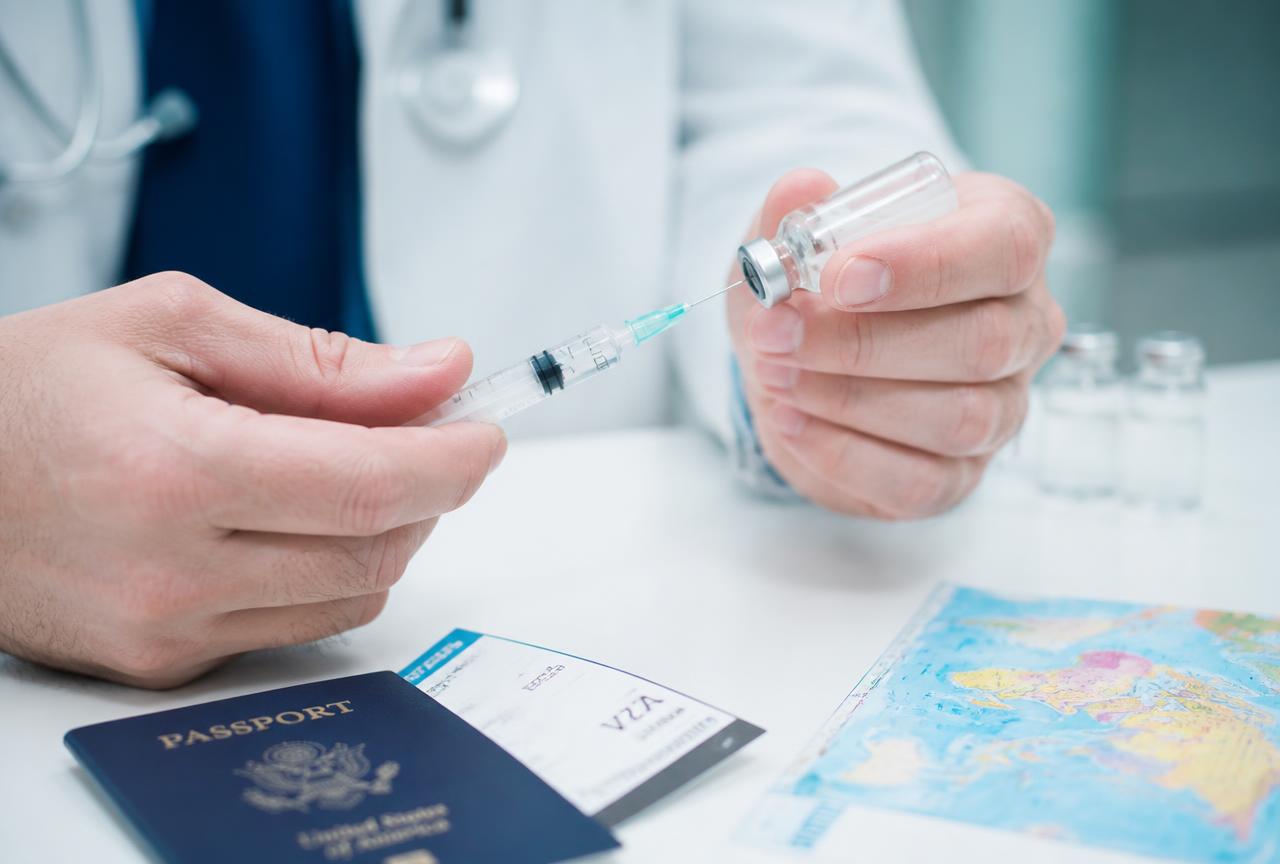 Doctor preparing a travel vaccine beside a passport and world map